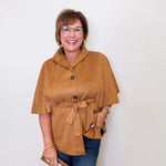 Woman wearing a brown jacket and blue jeans against a white background