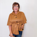 Woman wearing a brown jacket and blue jeans against a white background