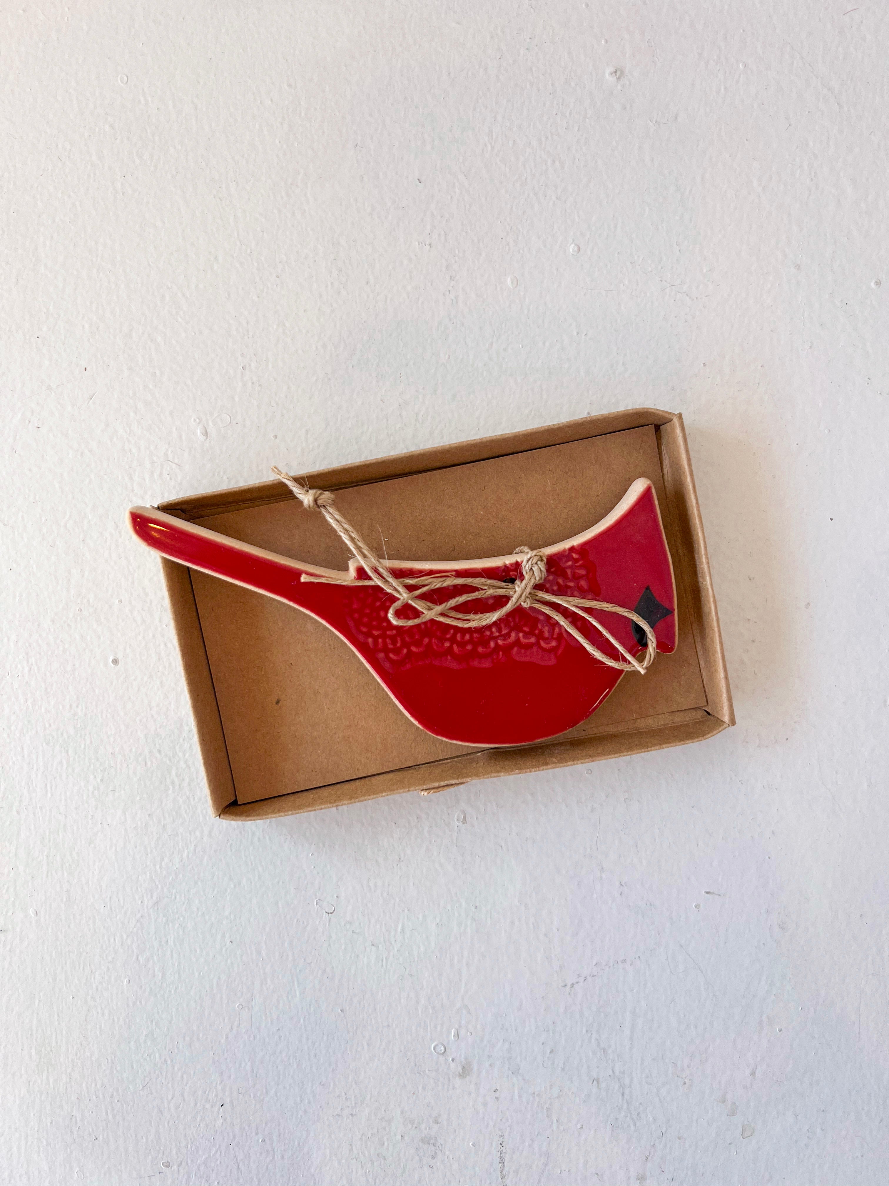 Red ceramic spoon rest in a cardboard box on a white background