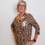 Woman wearing a leopard print dress with floral accents against a white background