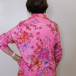 Person wearing a pink floral blouse against a white background