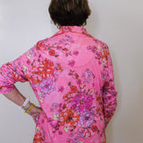 Person wearing a pink floral blouse against a white background