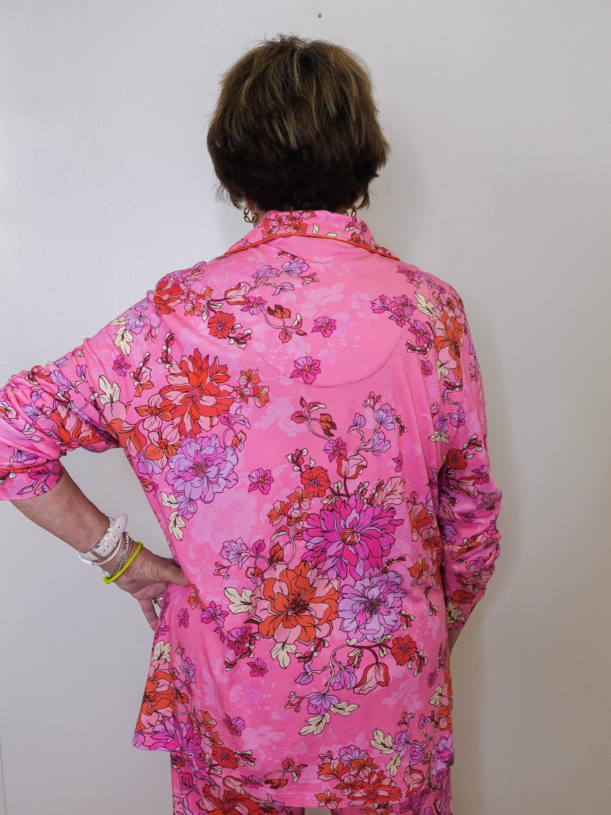 Person wearing a pink floral blouse against a white background