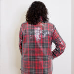 Person wearing a red and black plaid sequin jacket against a white background