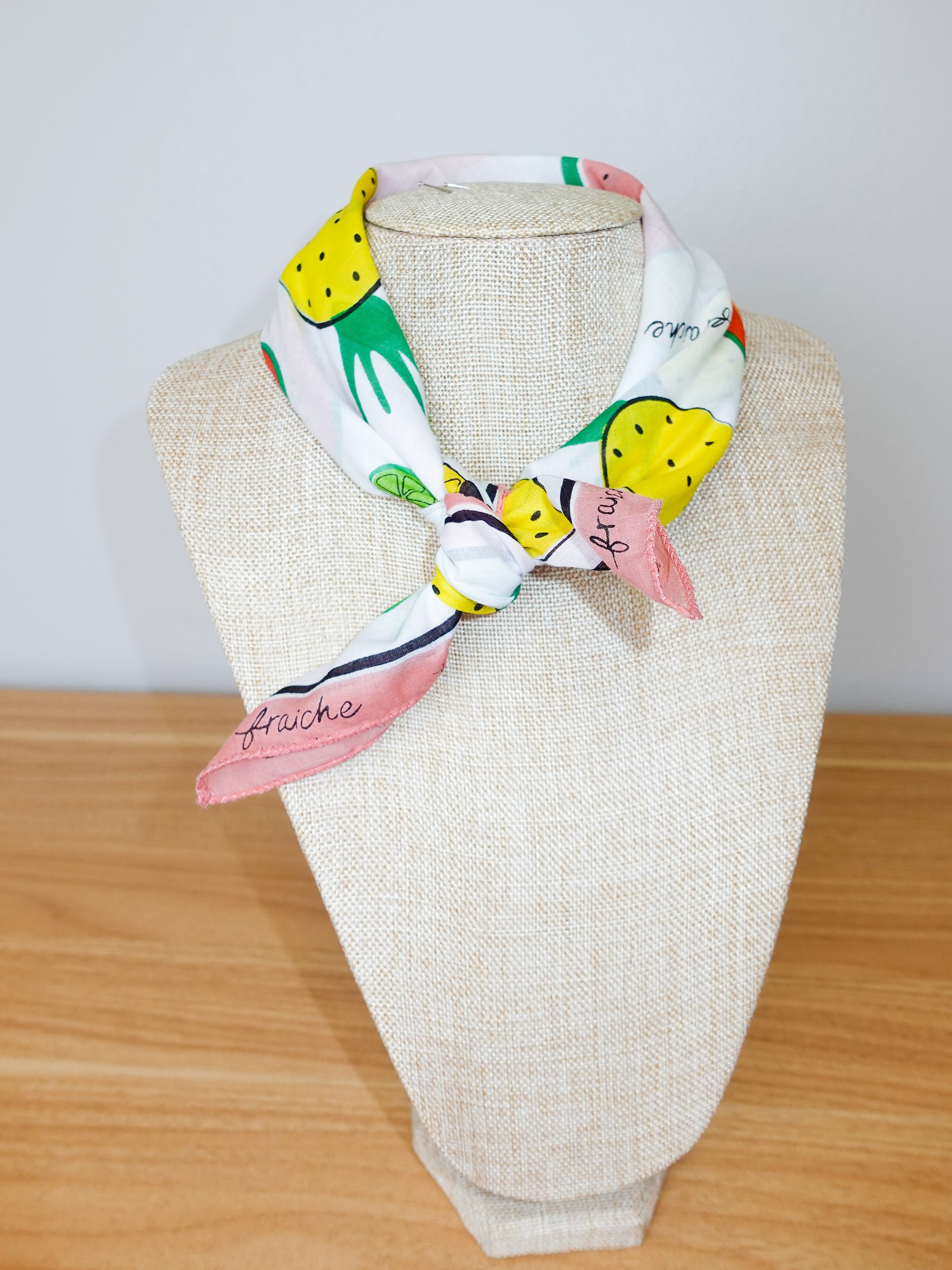 Colorful scarf with fruit pattern on a mannequin head against a white background