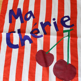 Striped fabric with 'Ma Chérie' text and cherries on a wooden surface