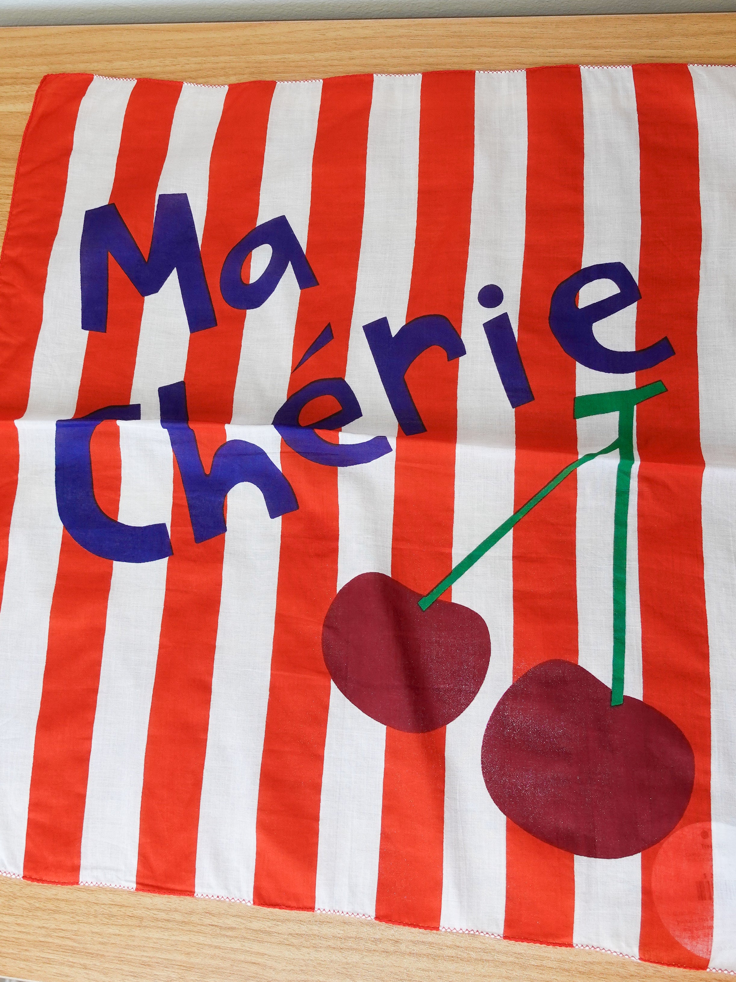 Striped fabric with 'Ma Chérie' text and cherries on a wooden surface