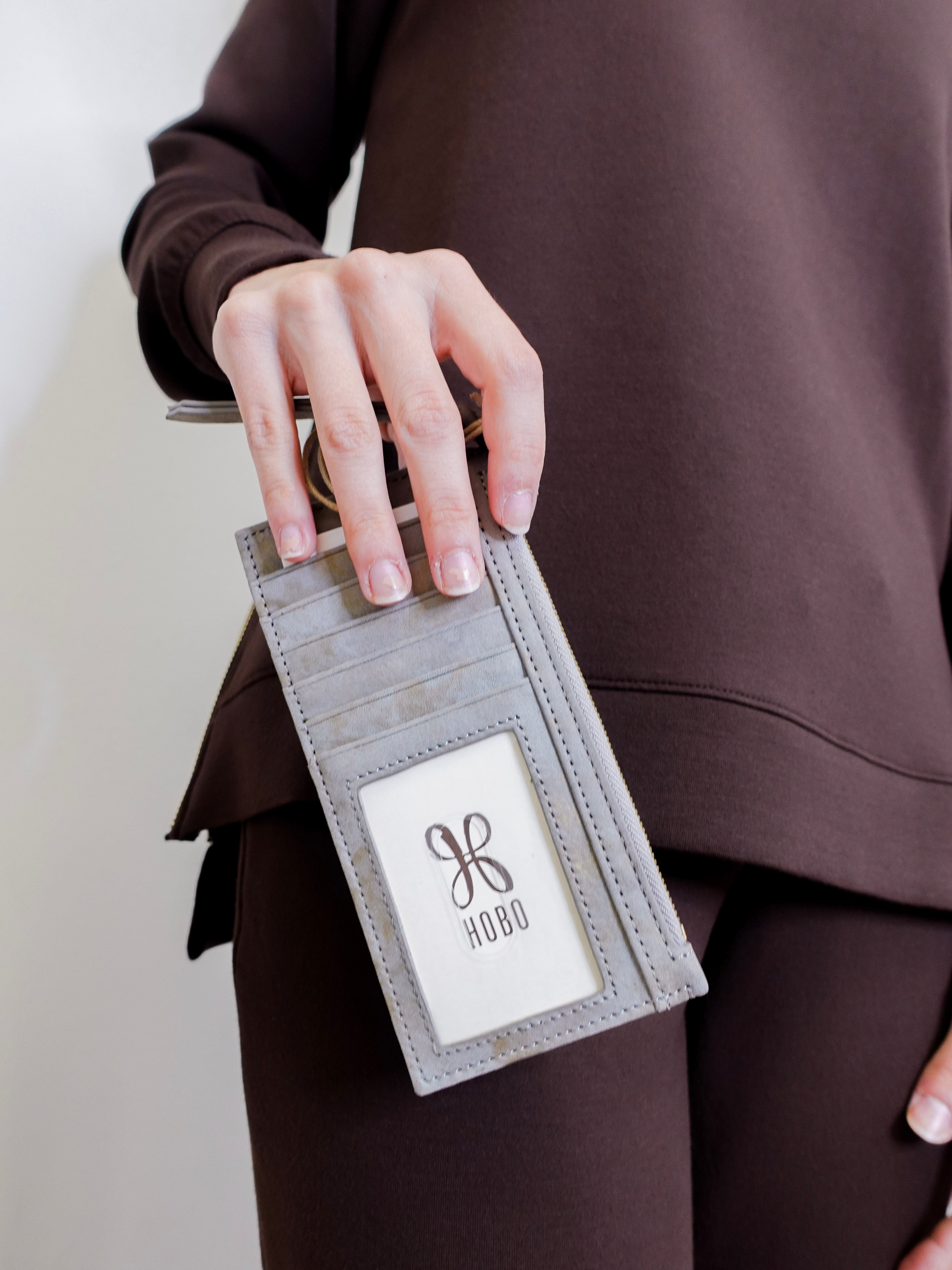 woman holding the Beige cardholder with zipper on a white background