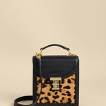Small black handbag with a leopard print pocket on a beige background