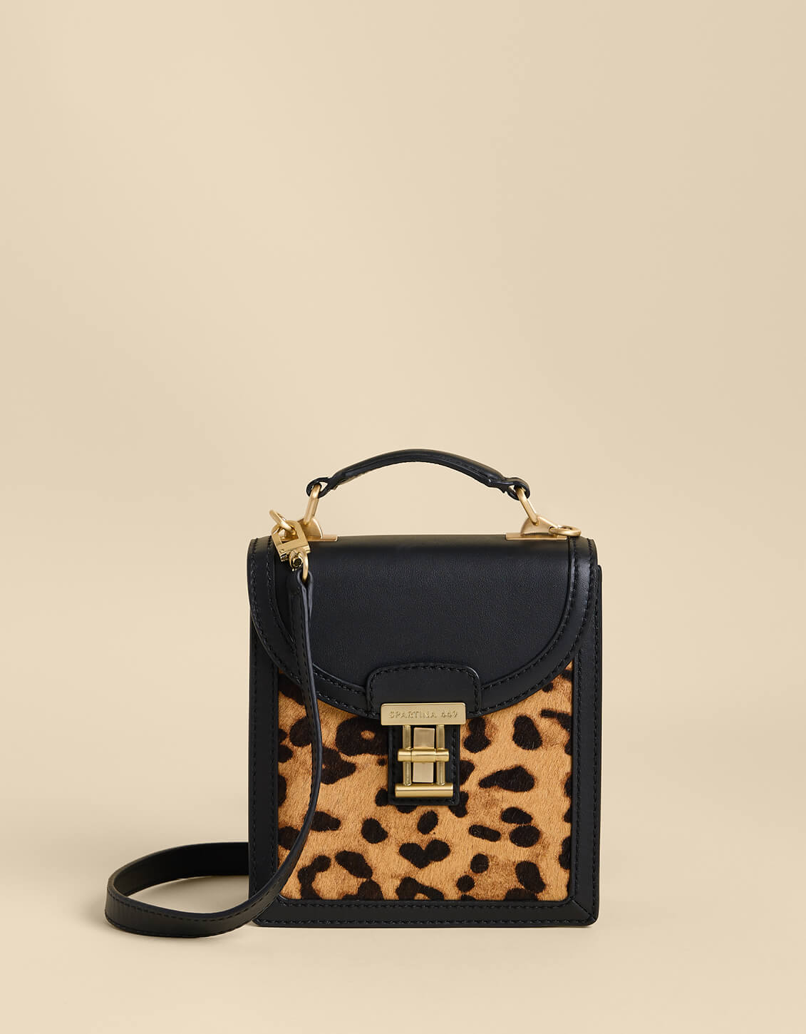 Small black handbag with a leopard print pocket on a beige background