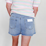 Person wearing a striped shirt and denim shorts with a white background