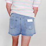 Person wearing a striped shirt and denim shorts with a white background