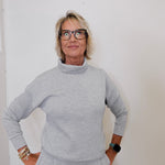Person wearing a gray outfit against a white background