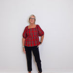woman wearing a plaid blouse against a white background. 