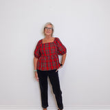 woman wearing a plaid blouse against a white background. 