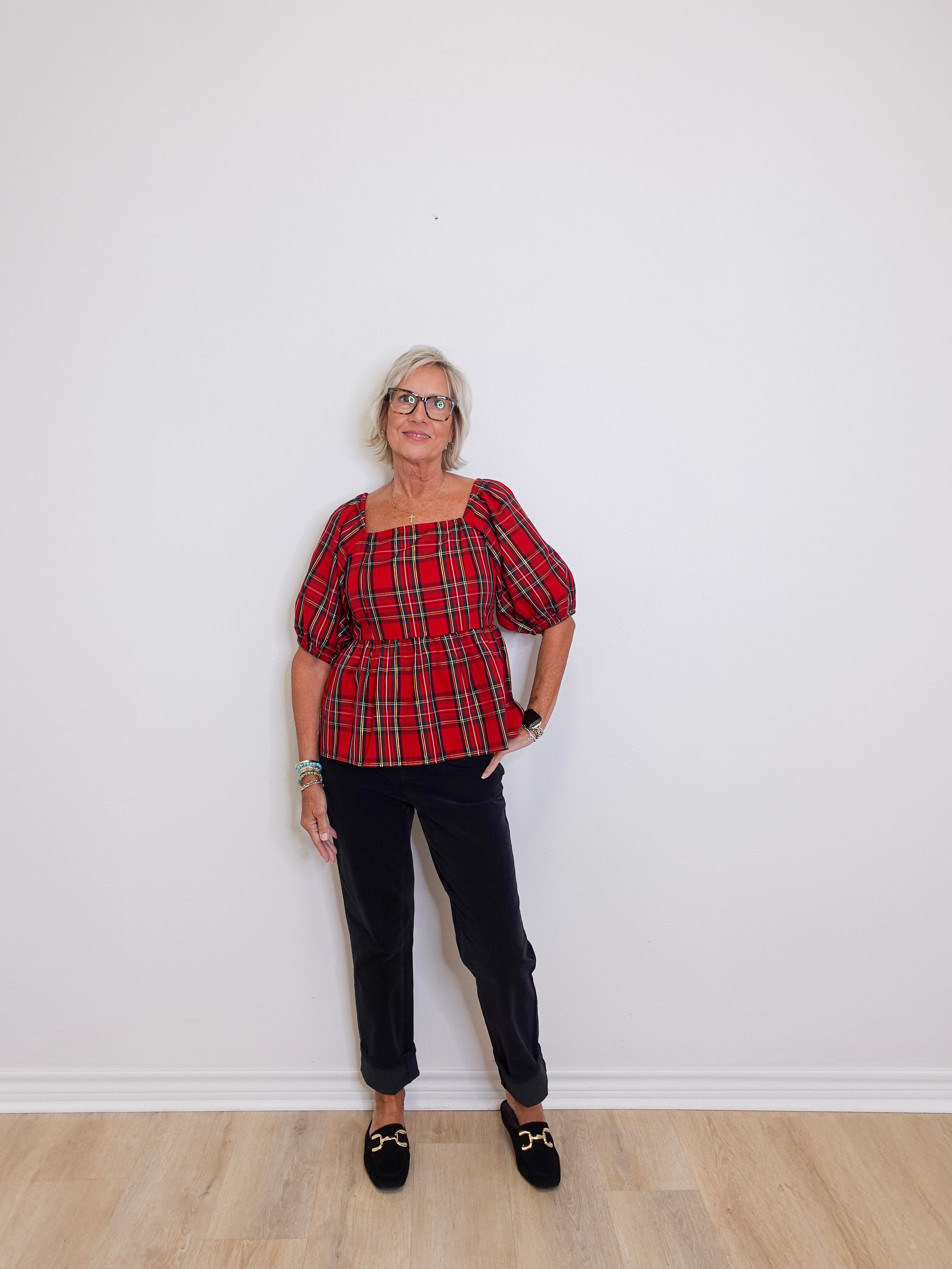woman wearing a plaid blouse against a white background. 