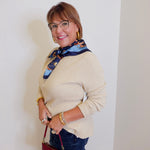 woman wearing a tan waffle knit top holding a burgundy hardback against a white background. 