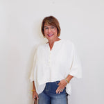 Woman wearing a white blouse and blue jeans against a plain background