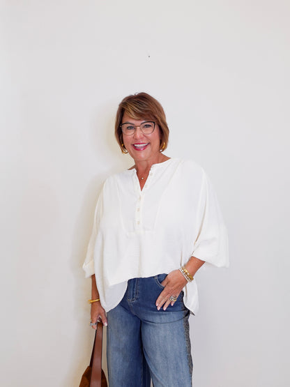 Woman wearing a white blouse and blue jeans against a plain background