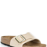 Beige sandal with a gold buckle on a white background