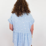 Person wearing a light blue blouse with star patterns on a plain background