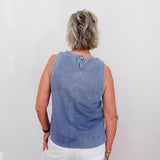 Person wearing a blue denim sleeveless top against a white background