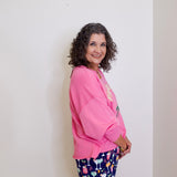 Woman wearing a pink sweatshirt and patterned shorts against a plain background