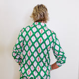Person wearing a green patterned shirt against a white background