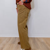 Person wearing brown pants and leopard print shoes against a white wall.