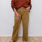 Person wearing a brown sweater and tan pants with leopard print shoes on a white background