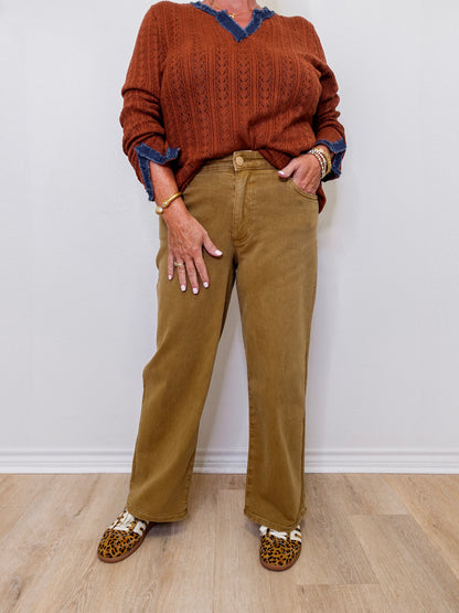 Person wearing a brown sweater and tan pants with leopard print shoes on a white background