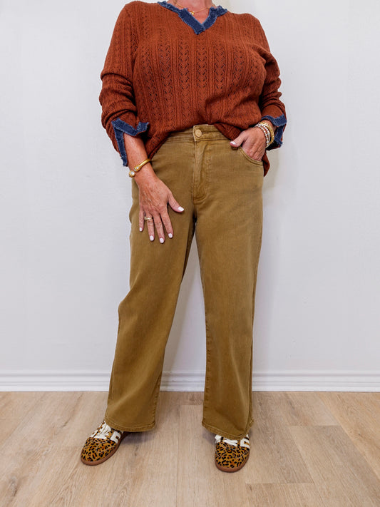 Person wearing a brown sweater and tan pants with leopard print shoes on a white background