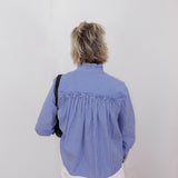 Person wearing a blue checkered blouse with a plain background