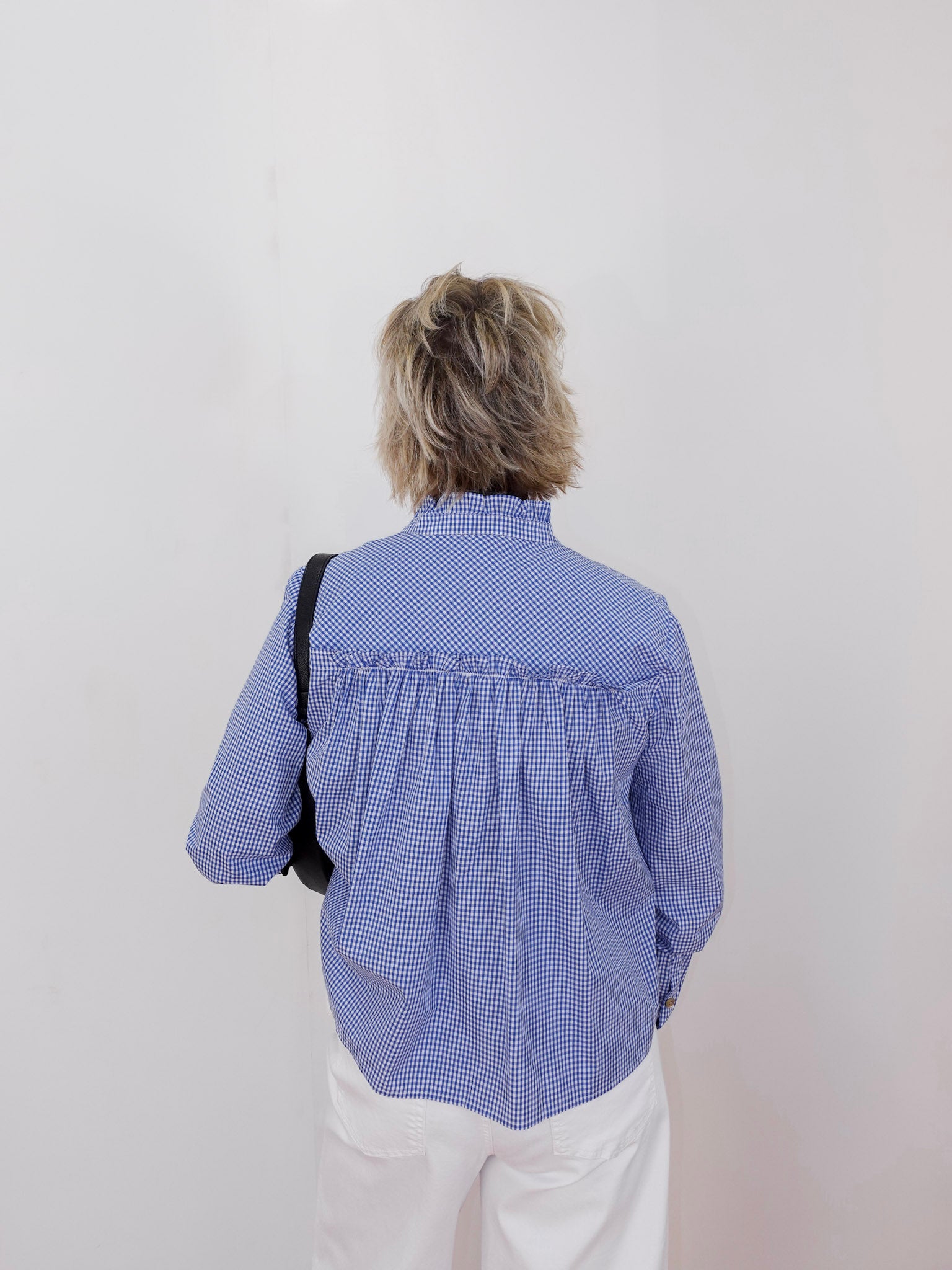 Person wearing a blue checkered blouse with a plain background