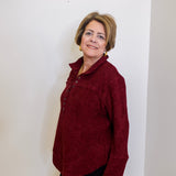 Woman wearing a casual wine color chenille henley top with grommet accents in front a white background 

