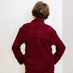 Person wearing a maroon sweater against a white background