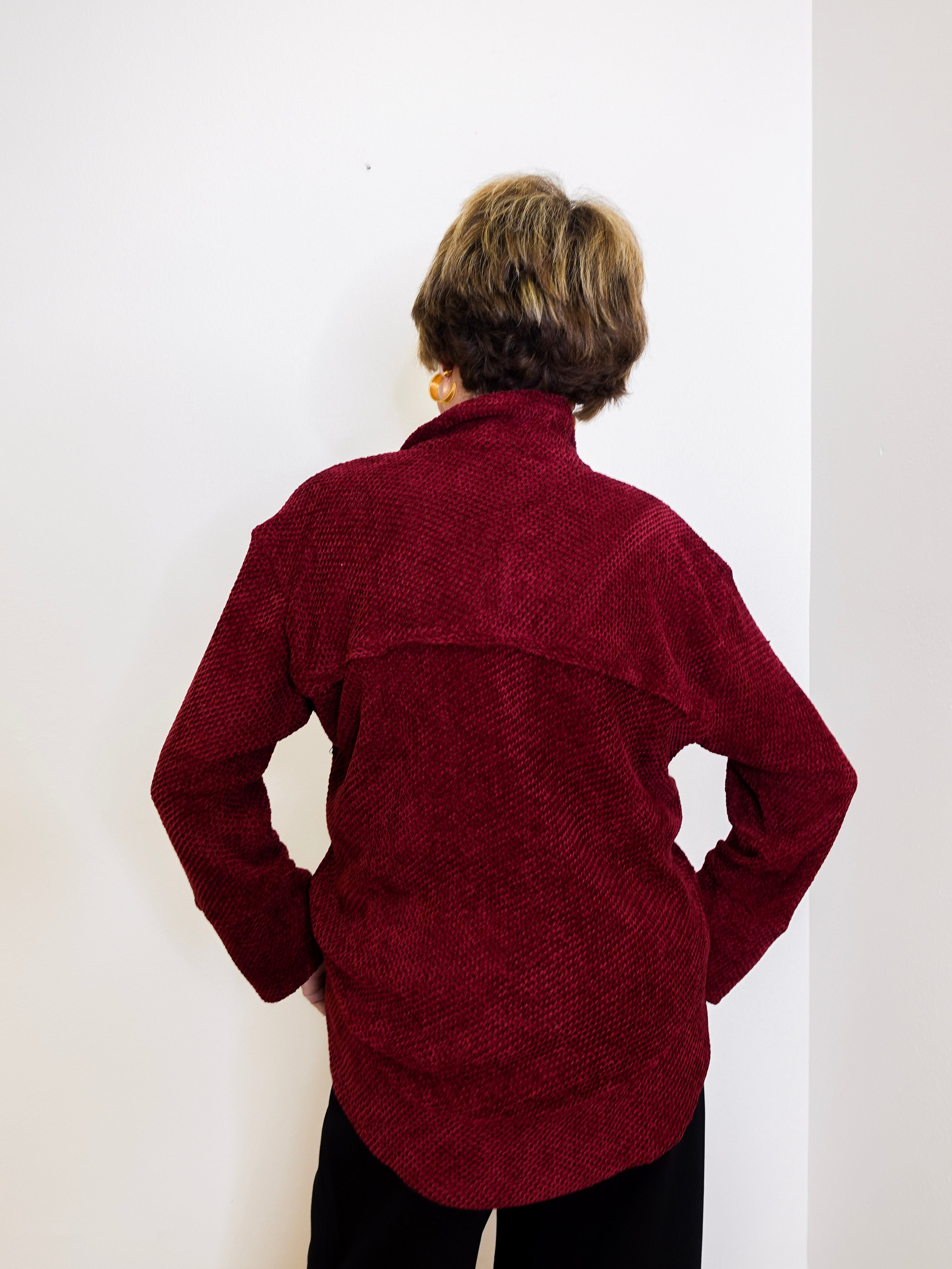 Person wearing a maroon sweater against a white background