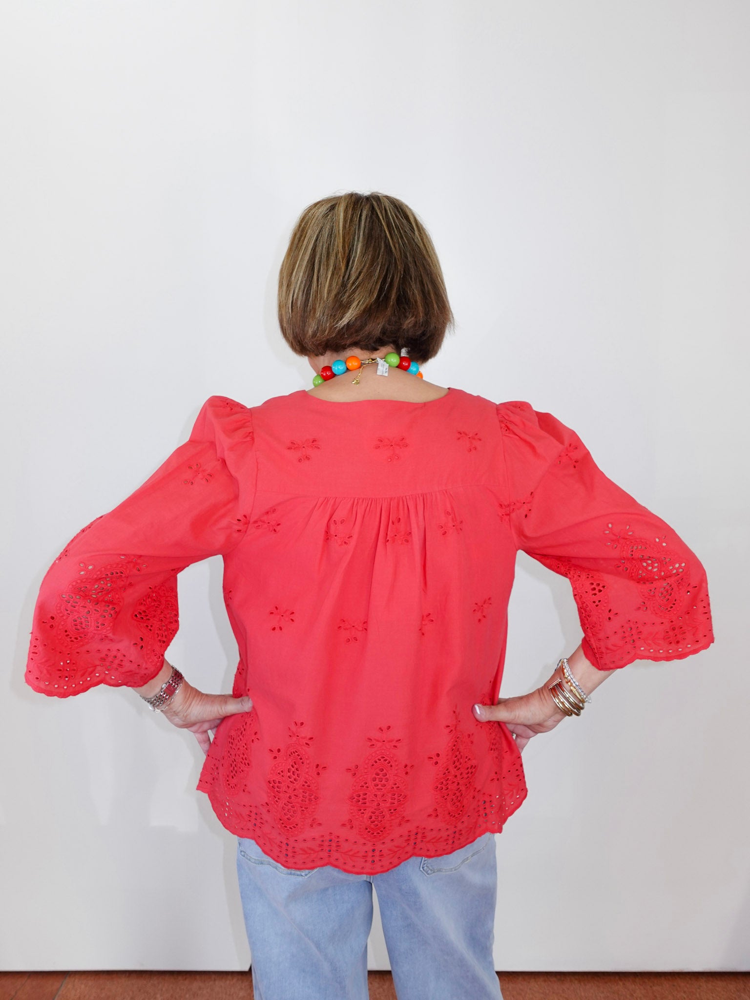 Person wearing a coral blouse with floral patterns against a white background