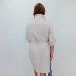 Person wearing a striped dress with a white wall background