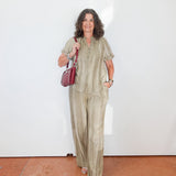 Woman in a green outfit holding a red bag against a white wall.