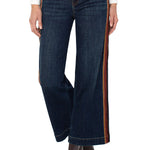 Dark blue jeans with brown side stripes worn by a person on a white background