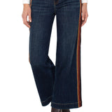 Dark blue jeans with brown side stripes worn by a person on a white background