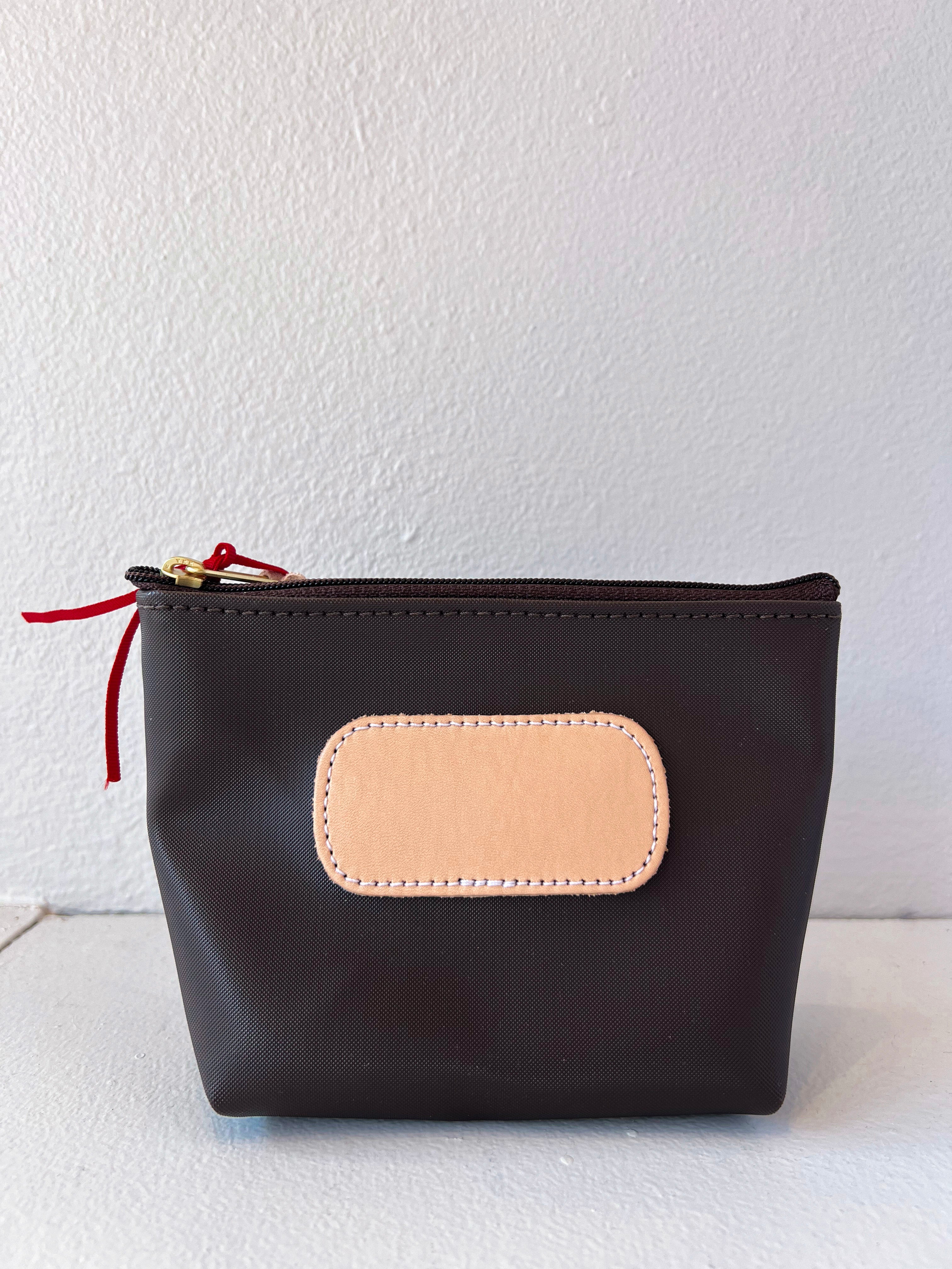 Black pouch with a beige patch and red zipper on a white background