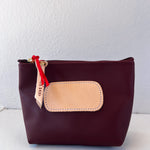 Brown pouch with beige patch and red zipper on a white background