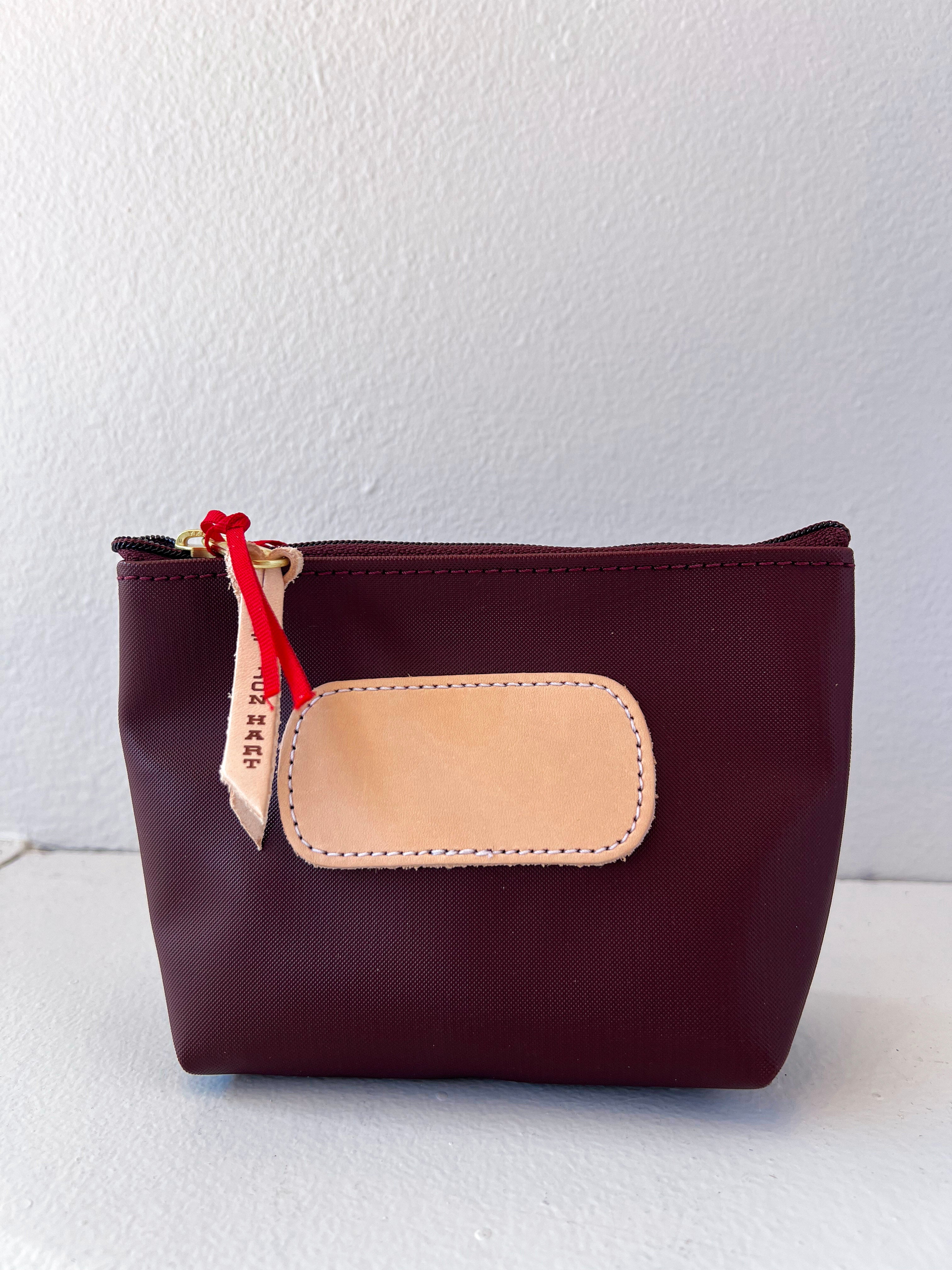 Brown pouch with beige patch and red zipper on a white background