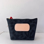 Black patterned pouch with a beige patch on a white background