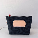 Black patterned pouch with a beige patch on a white background