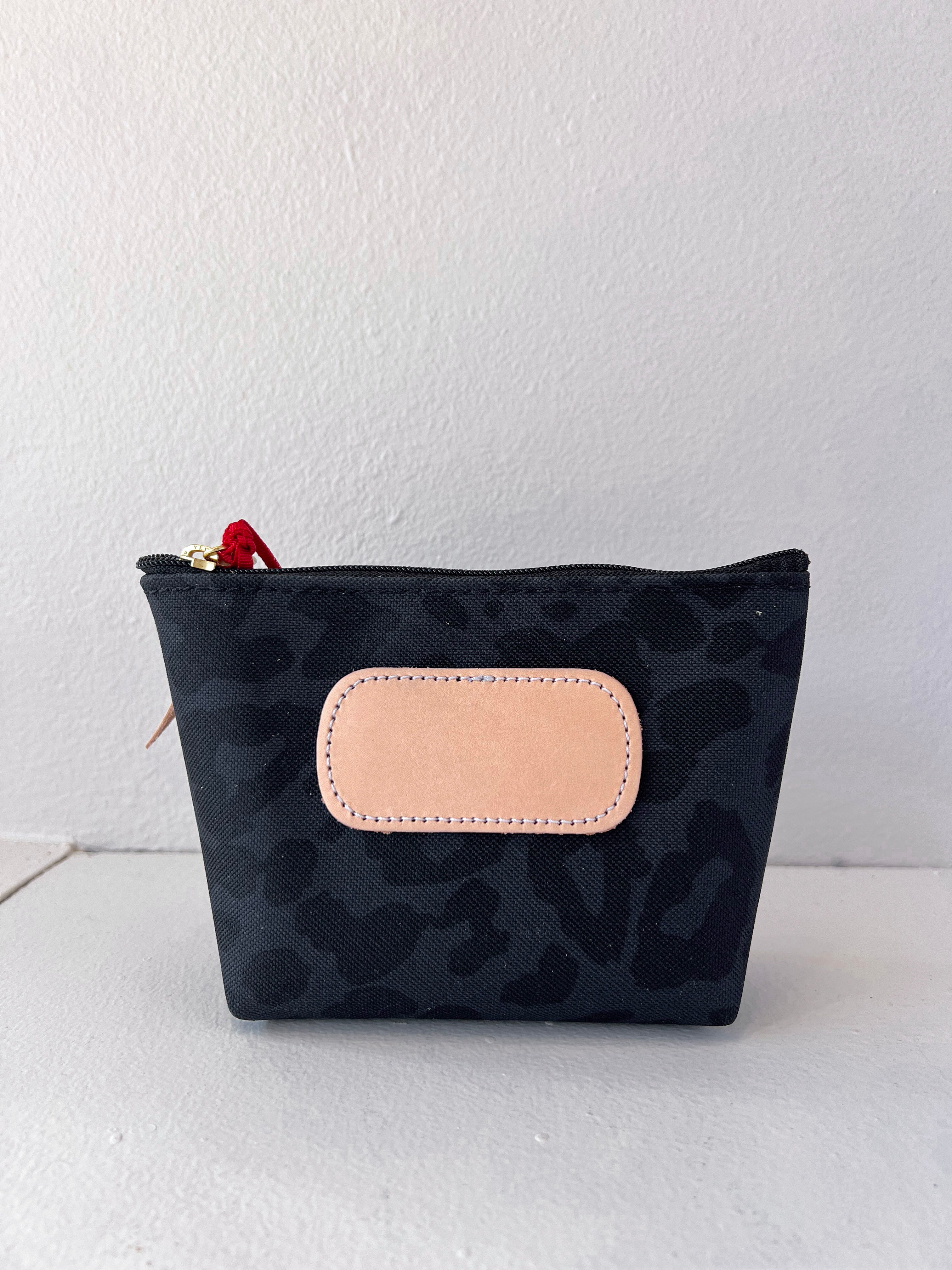 Black patterned pouch with a beige patch on a white background