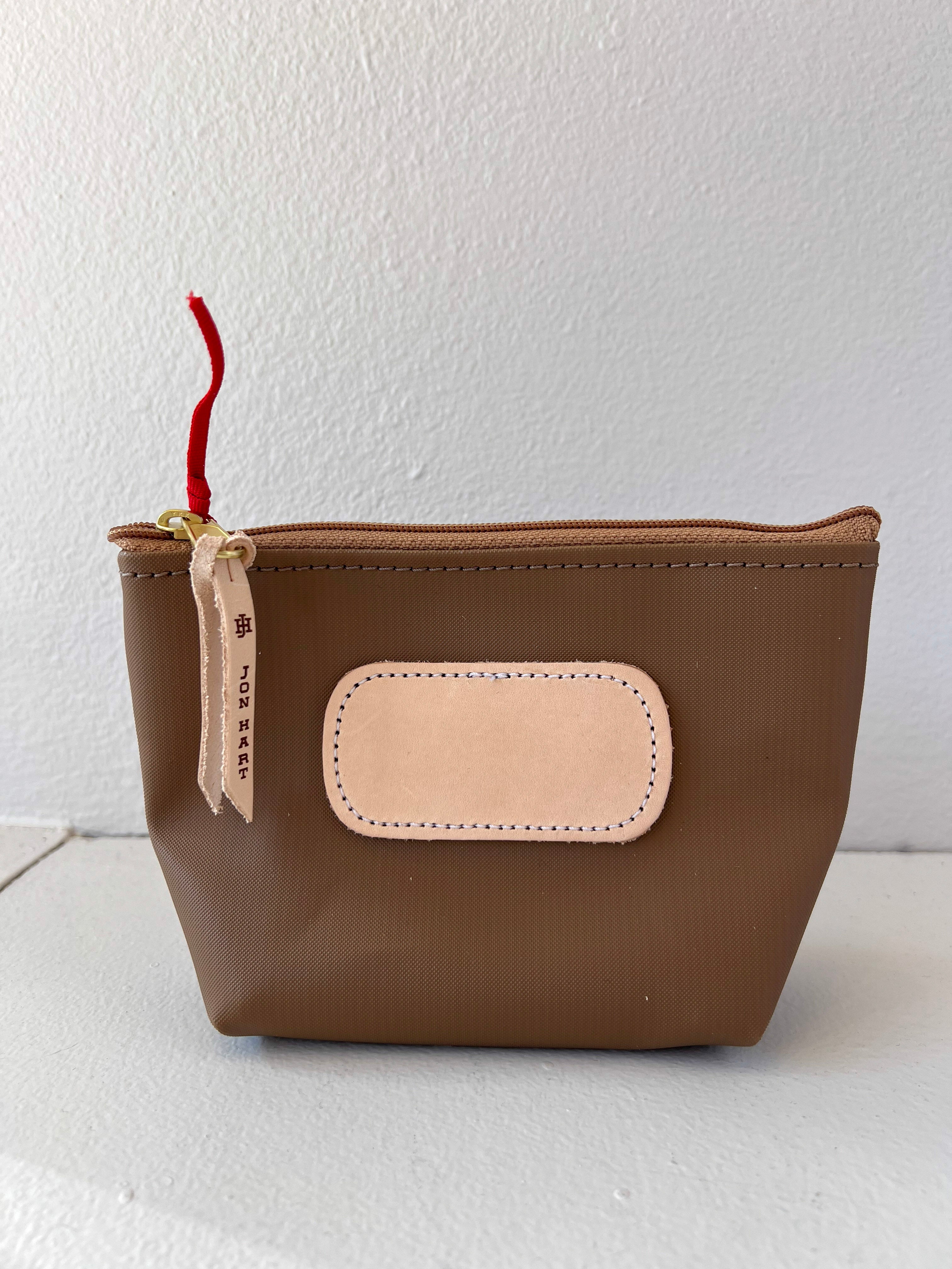 Brown pouch with beige patch and red string on a white background