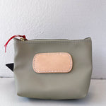 Gray pouch with a beige patch and red zipper pull on a white background